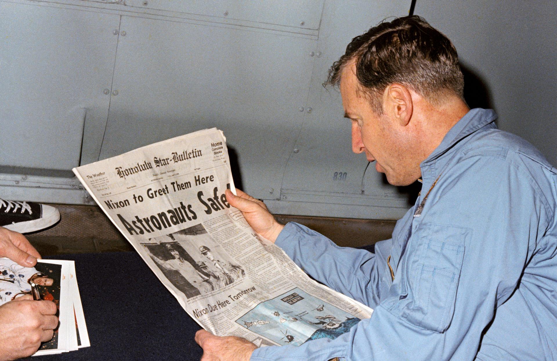 Astronaut in quarantine reading newspaper about Nixon greeting astronauts